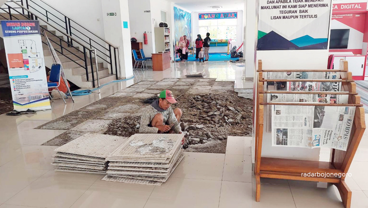 PERBAIKAN: Pekerja melakukan perbaikan lantai perpustakaan yang rusak. Pengunjung dipastikan tidak terganggu proses perbaikan. (LUKMAN HAKIM/RDR.BLORA)
