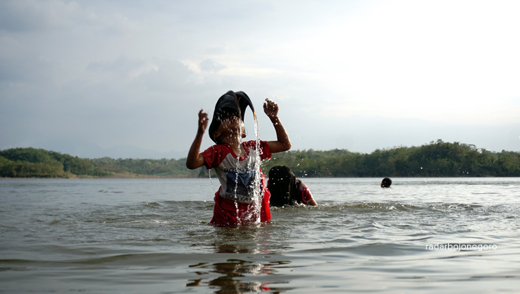 SEGAR: Anak-anak bermain air dan berenang di tepi Waduk Gongseng. Waduk berada di Kecamatan Temayang ini belum dibuka, hanya warga lewat jalur alternatif. (AHMAD HAKAM ALGHIVARI/RDR.BJN)