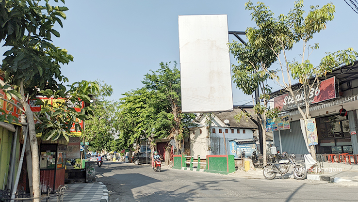 MELINTANG JALAN: Papan reklame di Jalan Rajawali ini cukup besar. Tampak pengendara motor melintas di bawahnya. (DHANI WAHYU ALFIANSYAH/RDR.BJN)