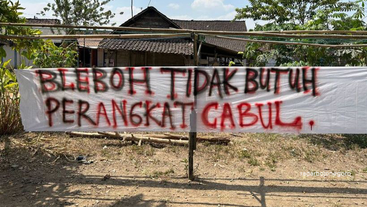 SERUAN WARGA: Warga Desa Bleboh membentangkan spanduk berisi seruan moral tentang penggerebekan sekdesnya. (RAHUL OSCARRA DUTA/RDR.BJN)