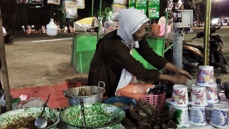 MELEGENDA: Bu Sarpin sedang melayani pembeli lontong kikil. Kuliner ini cukup melegenda, tetap eksis sejak 1987. (YANA DWI KURNIYA/RDR.BJN)