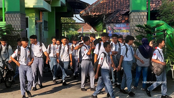 PULANG SEKOLAH: Pelajar SMAN 1 Cepu berhamburan keluar dari gerbang sekolah, bergantian menyeberang jalan. (LUKMAN HAKIM/RDR.BJN)