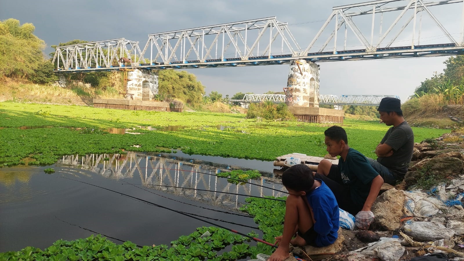 SERU: Jatmiko, warga Kecamatan Cepu bersama dua anaknya asyik memancing di bawah jembatan perbatasan Blora-Bojonegoro.(LUKMAN HAKIM/RDR.BJN)