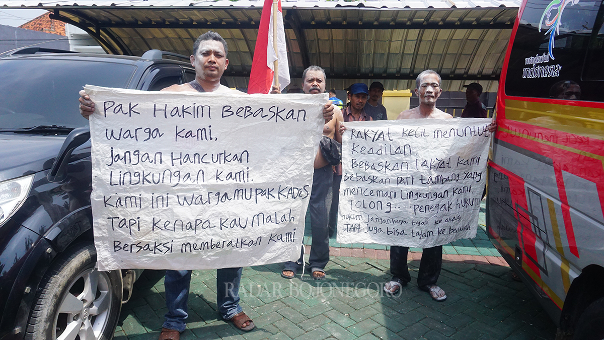 DUKUNGAN MORAL: Warga Desa Sumuragung membentangkan poster dukungan moral tiga temannya yang menjalani persidangan.   JADI SAKSI: Matasim, Kades Sumuragung, Kecamatan Baureno, dan sekretisnya Muhamad