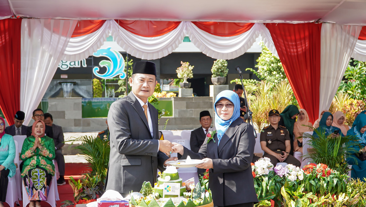 MENUJU LAMONGAN SEHAT: Bupati Lamongan, Dr. H. Yuhronur Efendi, MBA menyerahkan potongan tumpeng dalam puncak HKN ke-59 kepada Plt. Kepala Dinas Kesehatan Lamongan, dr. Herwidyah Sidhayatri.