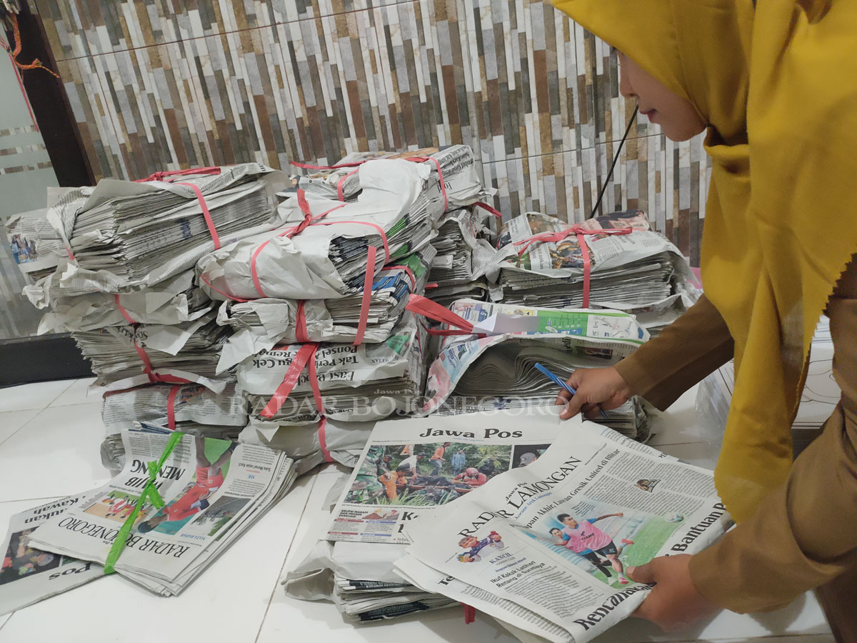 HITUNG DULU: Ketua IGTKI Kecamatan Kedungpring, Ummus Sholikah,S.s, dan tumpukan koran untuk bahan menempel dikertas. (ASIP A/RADAR LAMONGAN)