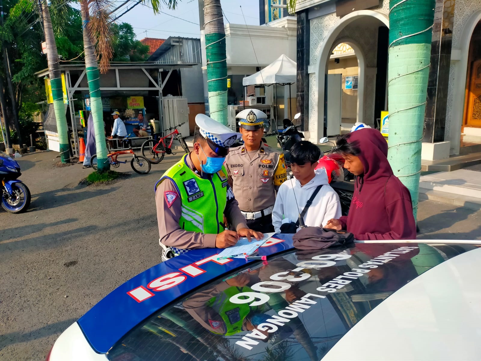 TULIS SURAT TILANG: Petugas Satlantas Polres Lamongan menilang pengendara motor yang tidak mematuhi ketentuan berlalu lintas.(IST/RDR.LMG)