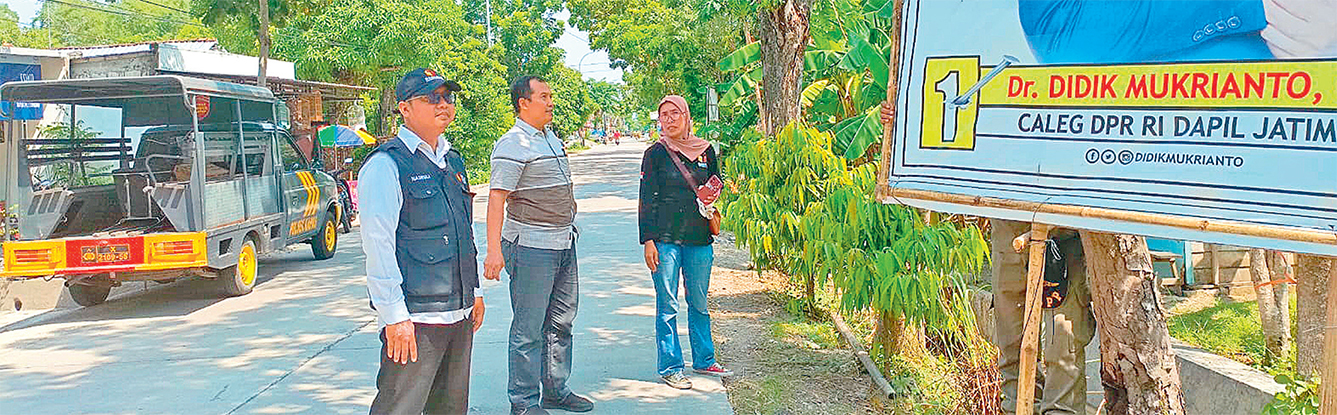 FOTO DULU: Penyelenggara Pemilu 2024 foto di depan APK salah satu peserta Caleg DPR RI. (WAHYU DHANI ALFIANSYAH/RADAR BOJONEGORO)