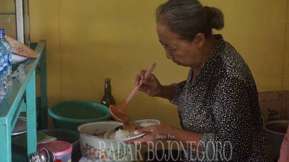 LEGEND: Usmiatun sedang melayani pesanan pembeli di warungnya. Pecel Rawon Usmiatun memiliki cita rasa khas. ( DEWI SAFITRI/RDR.BJN)