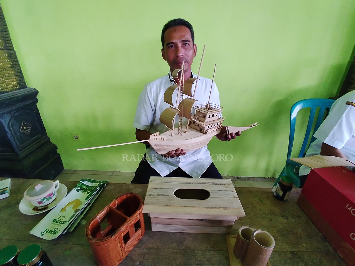 BERBAHAN BAMBU: Khosim menunjukkan salah satu karyanya yang berbahan bambu. (DEWI SAFITRI/RADAR BOJONEGORO)
