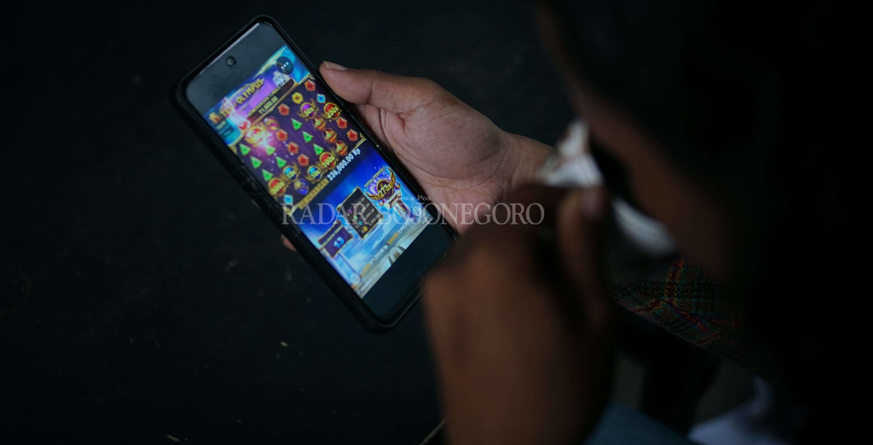 ILUSTRASI: Seorang pemuda sedang fokus memainkan salah satu permainan judi online jenis slot Pragmatic sambil menyesap kopi hitam. (HAKAM ALGHIVARI/RDR.BJN)