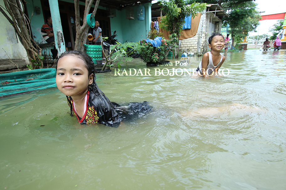 TERDAMPAK: Beberapa anak-anak di Dusun Gabus, Desa Tambakploso, Kecamatan Turi tampak kegirangan menjadikan banjir sebagai tempat berenang.  (ANJAR DWI PRADIPTA/RADAR LAMONGAN)