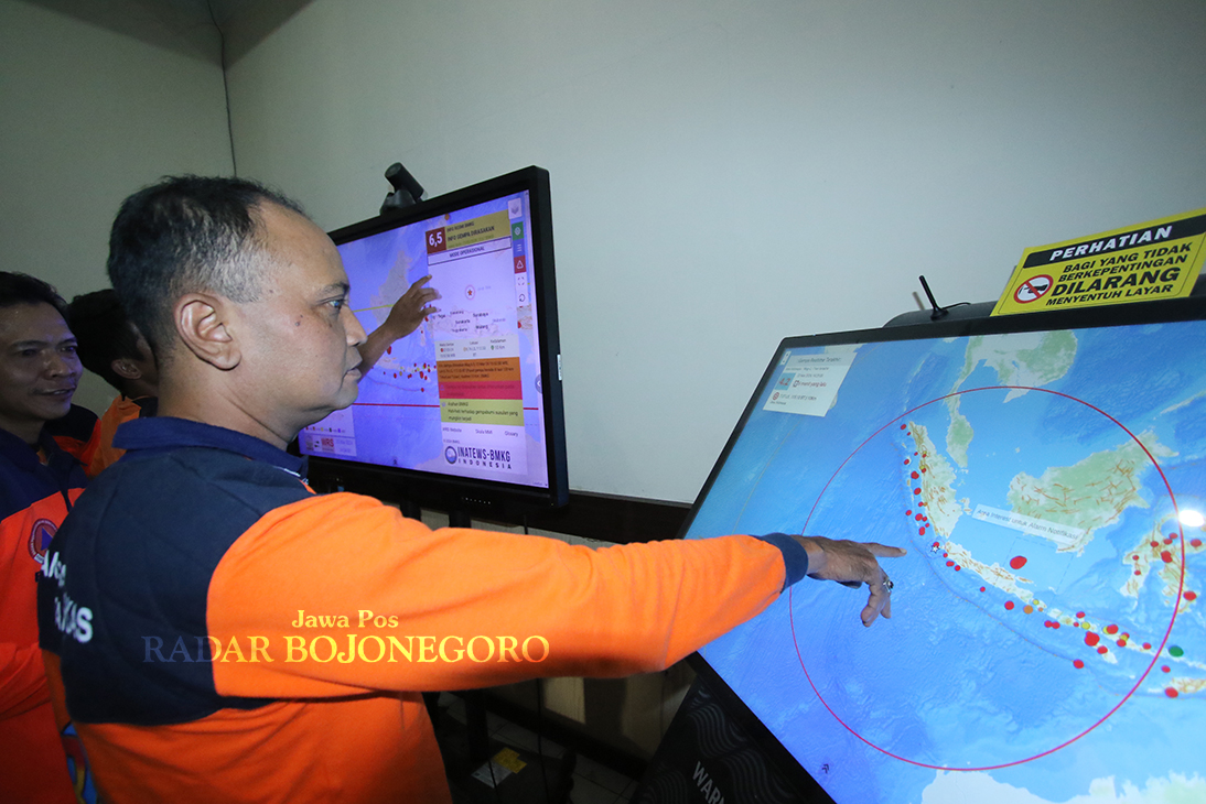 INTENS MEMANTAU: Petugas BPBD Lamongan memantau laporan BMKG dari monitor warning receiver system. (ANJAR DWI PRADIPTA/RADAR LAMONGAN)