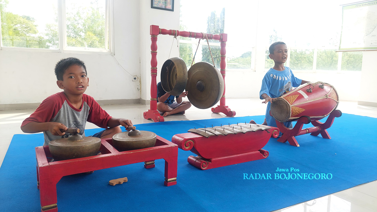 MAIN GAMELAN: Adanya alat gamelan di Perpustakaan Blora justru menjadi daya Tarik bagi anak-anak sekitar untuk datang dan rutin memainkannya setiap siang. (LUKMAN HAKIM/RADAR BOJONEGORO)