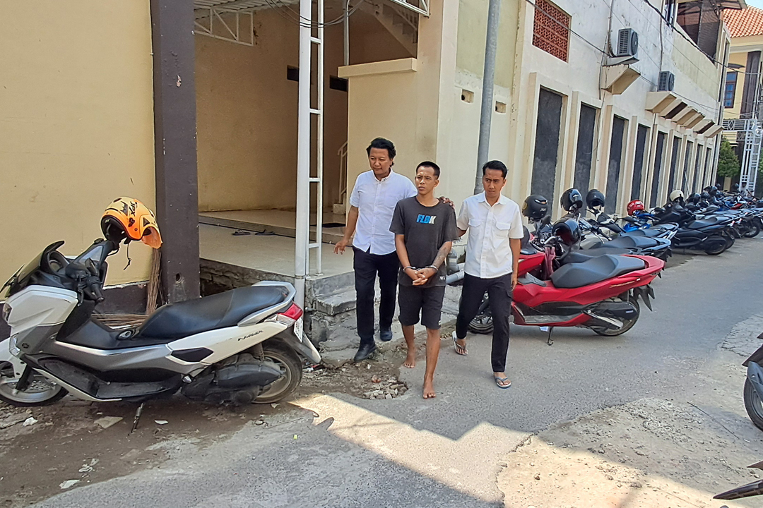 DIBORGOL: Roni Mustofa dikawal dua petugas sebelum menjalani pemeriksaan di Mapolres Lamongan.