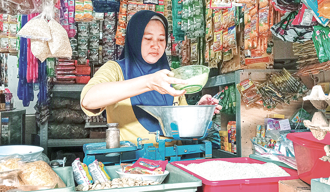 MENIMBANG BERAS: Pedagang di Pasar Bojonegoro Kota sedang menimbang beras. DKPP pastikan stok beras aman.