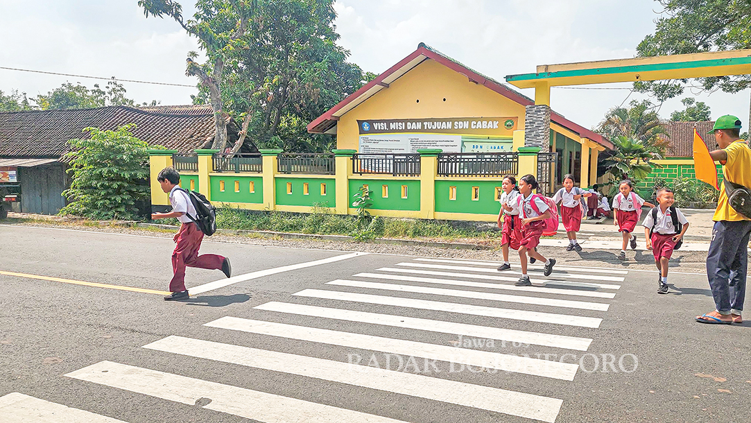 LAMA SEKOLAH: Siswa-siswi SDN Jiken berlarian menyeberang jalan saat pulang sekolah.