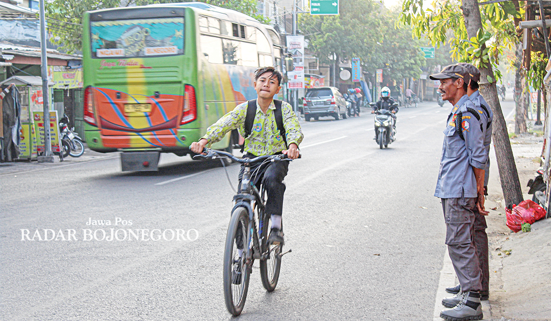 WAJIB DICONTOH: Seorang siswa SMP bersemangat mengayuh sepedanya saat berangkat ke sekolah. Wajib dicontoh, agar tidak ikut-ikutan mengendarai sepeda motor. (WAHYU DHANI ALFIANSYAH/RADAR BOJONEGORO)