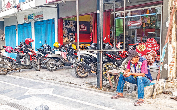 RETRIBUSI: Jukir resmi dinrumkimhub mengenakan rompi resmi saat bertugas. Tarif parkir motor Rp 1.000 dan tarif parkir mobil Rp 2.000. (LUKMAN HAKIM/RADAR BOJONEGORO)