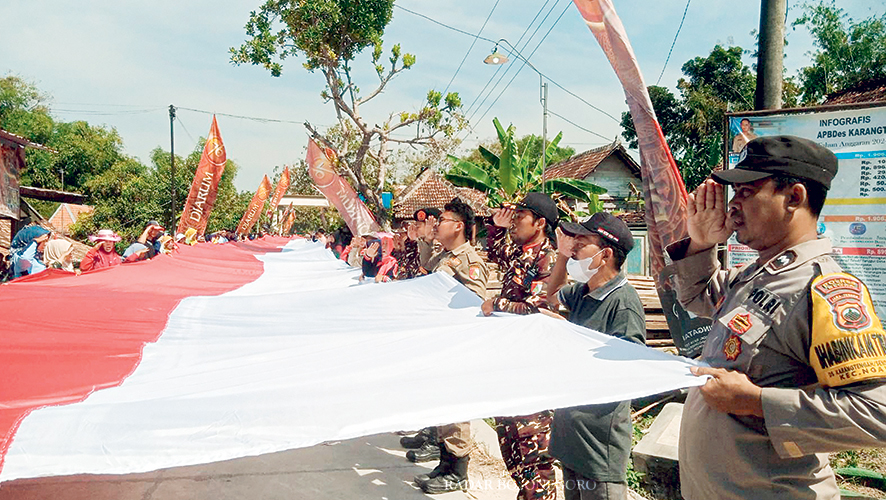 SEMARAK: Warga Desa Karangtengah kompak menjahit bendera merah putih sepanjang 79 meter dan lebar 3 meter secara manual. Kemudian, dibentangkan dan dikirab keliling