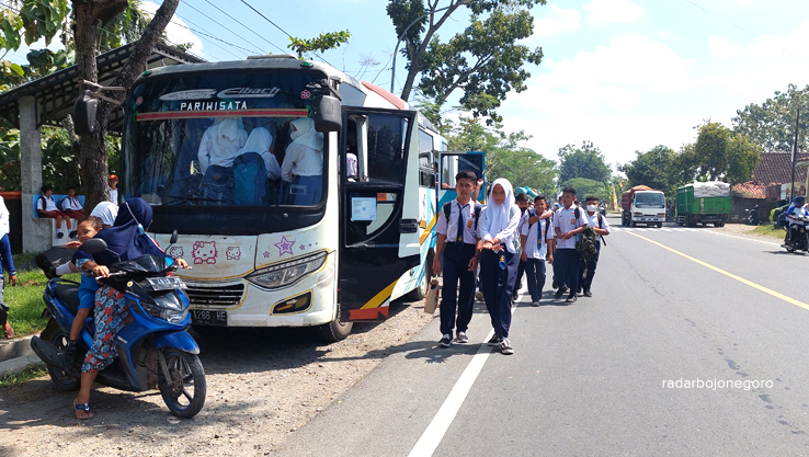 ANGKUTAN SEKOLAH: Siswa-siswi sedang menaiki bus yang rutin ngetem di depan SMPN 1 Sambong. (LUKMAN HAKIM/RADAR BOJONEGORO)