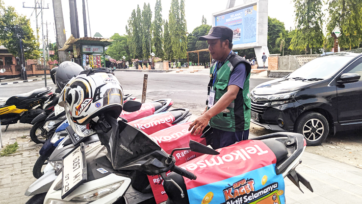 E-PARKIR: Juru parkir di kawasan pusat makanan di Koplakan dan Alun-Alun Blora mengalukan kartu dengan kode QRIS untuk uji coba pembayaran e-parkir. (M. LUKMAN HAKIM/RADAR BOJONEGORO)