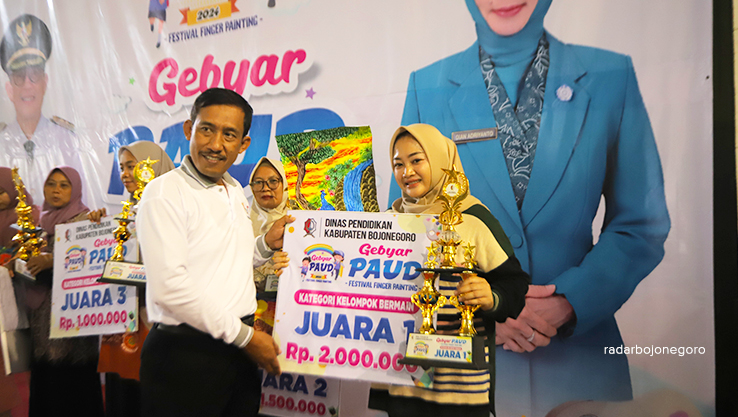 SERAHKAN PIALA: Kabid PAUD Disdik Bojonegoro Rasmadi menyerahkan piala kepada salah satu juara. (AHMAD NAWAF TF/ RADAR BOJONEGORO)