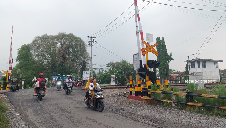 KESELAMATAN: Pengendara melintasi perlintasan sebidang yang sudah ada pos penjaga di Kelurahan Balun, Kecamatan Cepu. (LUKMAN HAKIM/RADAR BOJONEGORO)
