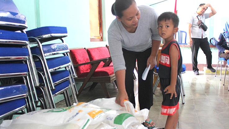 BANTUAN: Seorang ibu dan anak mengambil bantuan pangan berupa beras 10 kilogram di Kantor Pos Blora.