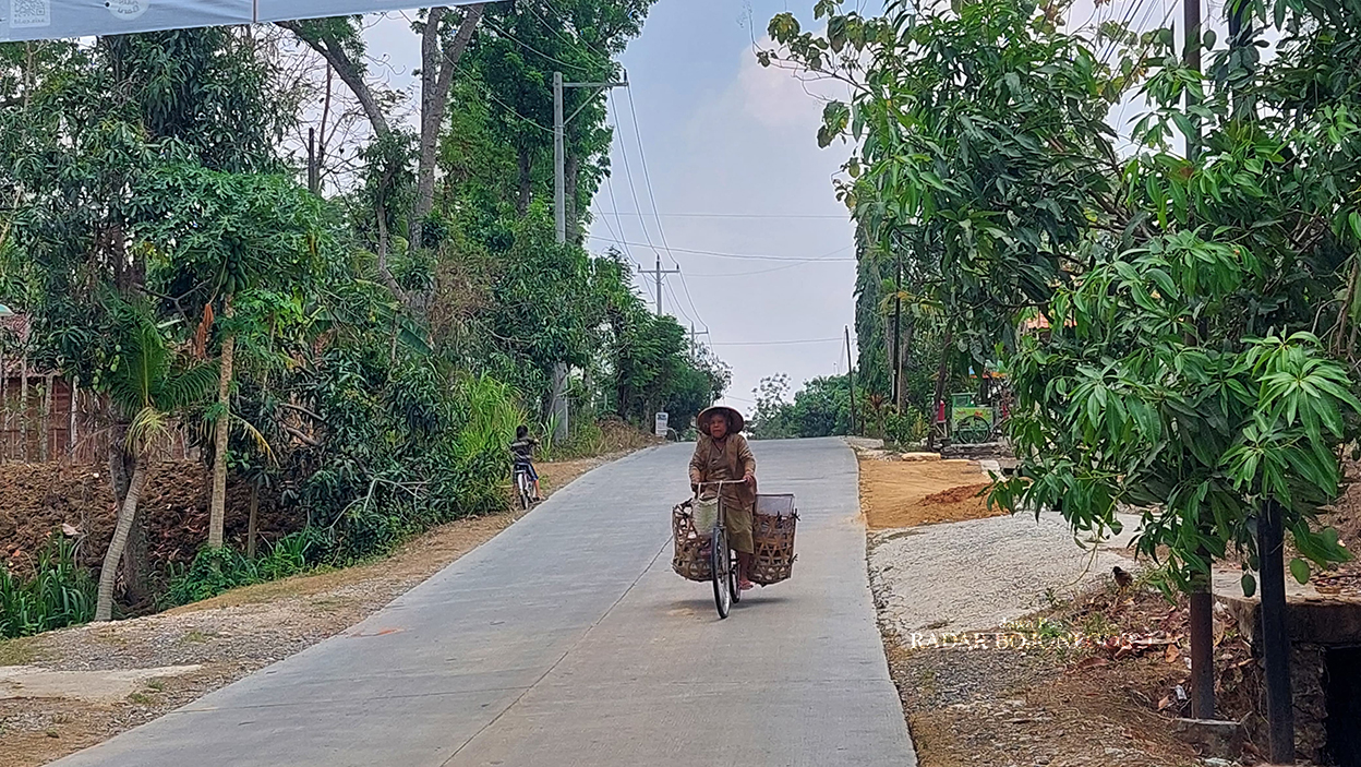 JALAN COR: Seorang perempuan paro baya mengayuh sepeda menyusuri ruas Jalan Blora-Randublatung yang sudah dibangun pemkab. (M. LUKMAN HAKIM/RADAR BOJONEGORO