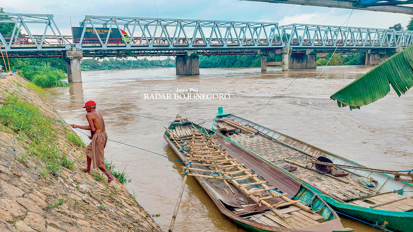 BENGAWAN SOLO: Seorang penambang sedang menyandarkan perahu penyeberangan di tepi Bengawan Solo turut Kecamatan Cepu kemarin (17/12).  (M. LUKMAN HAKIM/RADAR BOJONEGORO)