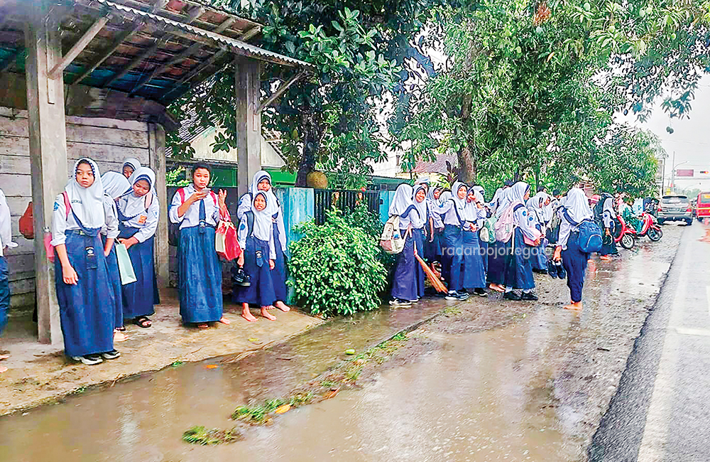 PELAJAR: Hujan mereda, siswa-siswi SMPN 1 Jepon berada di seberang jalan saat momen pulang sekolah.