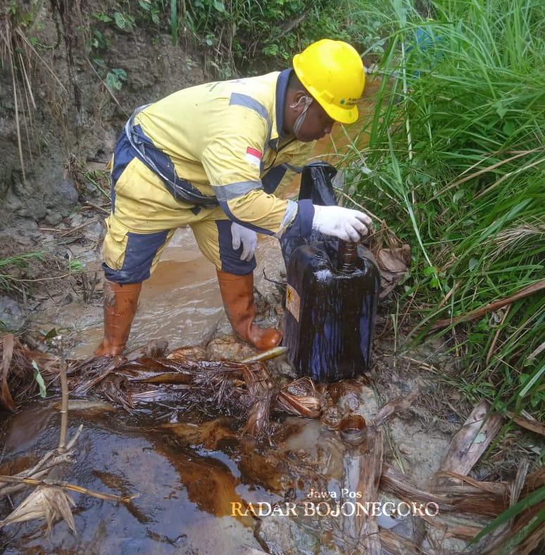 MENGAIS MINYAK: Salah satu warga tampak mengais lantung yang tercecer di saluran kali kemarin (14/2) pagi.(LUKMAN HAKIM/RADAR BOJONEGORO)