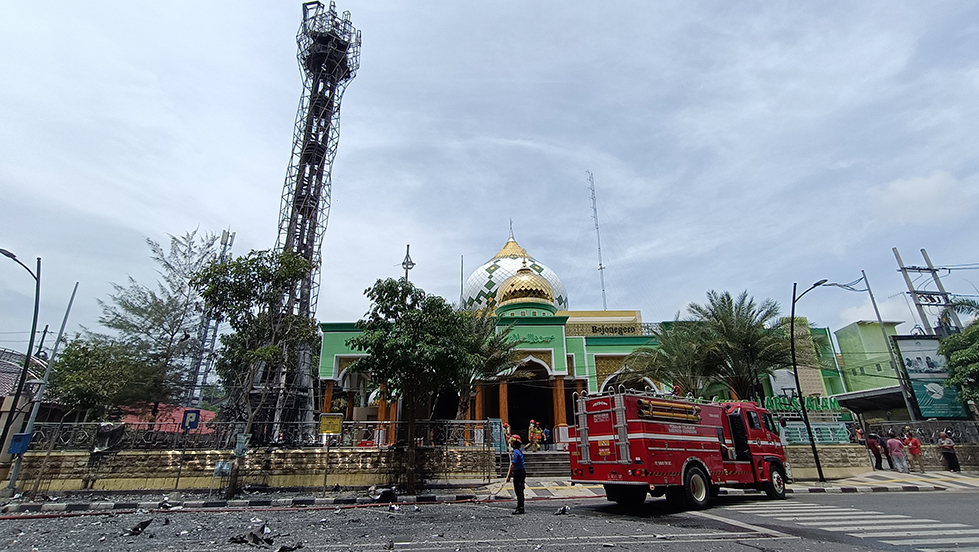 HANGUS: Petugas melakukan pembasahan di sekitar menara masjid untuk memastikan api di lokasi kejadian sudah padam.  (YUAN EDO/RADAR BOJONEGORO)