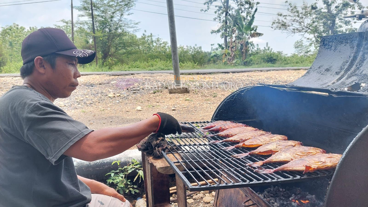 IKAN ASAP: Pedagang ikan asap di Kecamatan Cepu sedang memanggang ikan yang akan dijual di pinggir Jalan Raya Cepu-Blora. (M. LUKMAN HAKIM/RADAR BOJONEGORO)