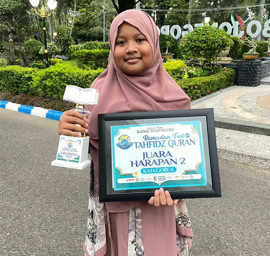 JUARA FAVORIT: Bilqis Nayla Yasni Syauqiyya memegang piala dan piagam Juara Favorit dan Harapan II  Kategori A Tahfidz Quran 2025 (IRVAN RAMADHON/RADAR BOJONEGORO)
