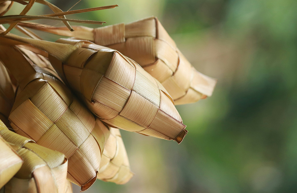 ketupat adalah makanan berbahan dasar beras yang dibungkus dengan anyaman janur .