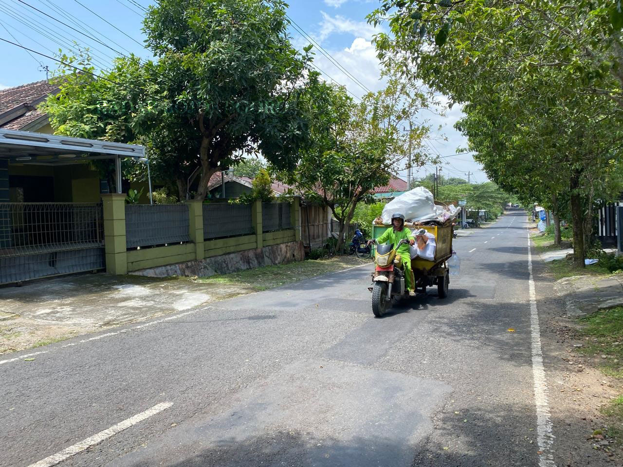 ANGKUT SAMPAH: Petugas kebersihan mengangkut sampah menggunakan sepeda motor roda tiga  menuju TPA.  (M. LUKMAN HAKIM/RADAR BOJONEGORO)