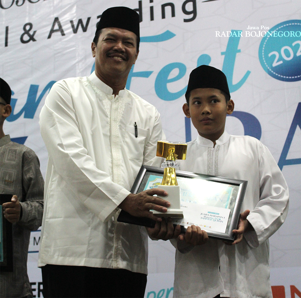 SEMANGAT: Omar Xaviero Ghazali menerima hadiah dan piagam Juara Harapan 1 Kategori B Tahfidz Quran 2025. (DHANI WAHYU ALFIANSYAH/RADAR BOJONEGORO)