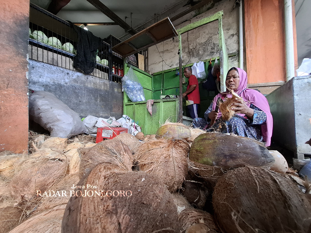 PEDAGANG: Seorang penjual kelapa parut di Pasar Kalitidu mengabarkan harga barang dagangannya sedang naik akibat tingginya permintaan selama momen Lebaran. (DEWI SAFITRI/RADAR BOJONEGORO)