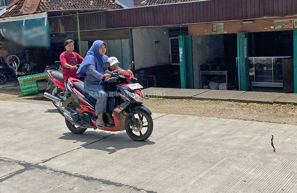 JALAN RAYA: Seorang ibu memacu motor sambil membonceng anaknya di Ruas Jalan Bogorejo-Jepon.