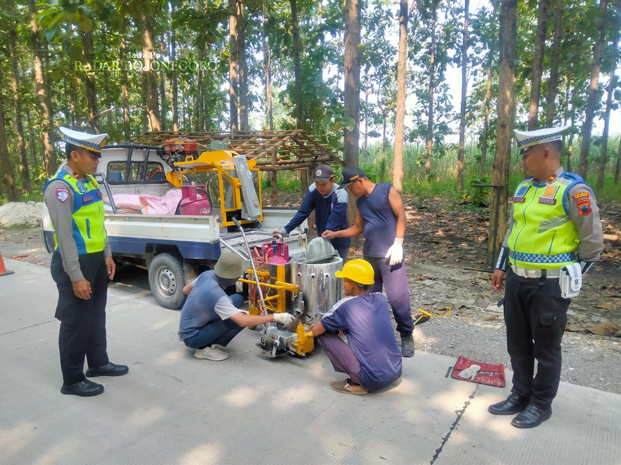 PREVENTIF: Petugas kepolisian memasang pita kejut di jalan Getas-Ngawi agar kecepatan tiap kendaraan yang melintas bisa terkendali. (RAHUL OSCARRA DUTA/RADAR BOJONEGORO)