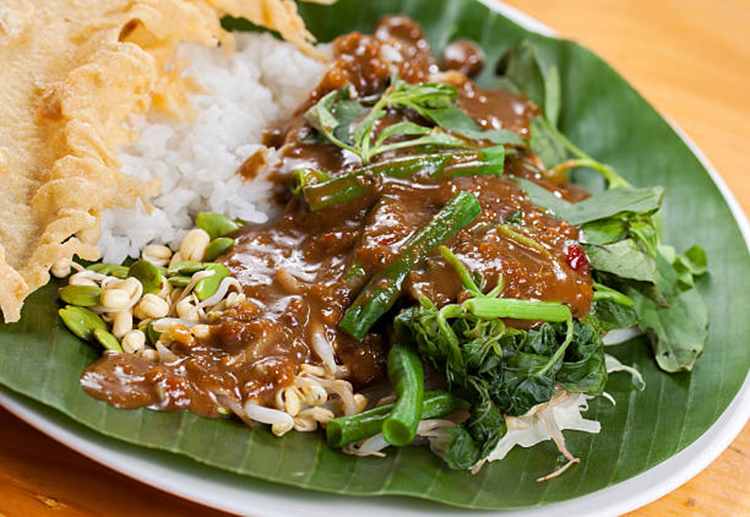 Nasi pecel is a Javanese rice dish served with mix vegetables and spicy peanut sauce