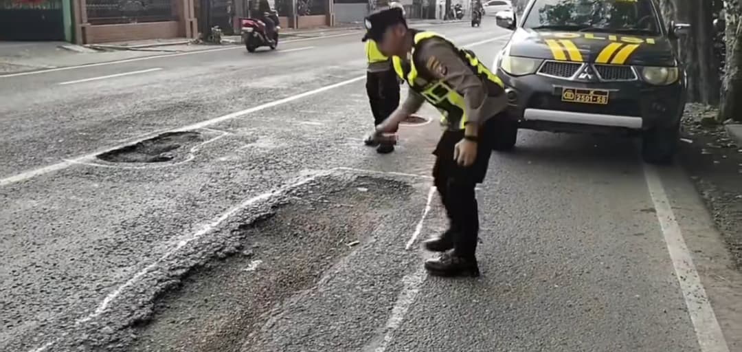 BERLUBANG: Polisi menandai jalan berlubang yang membahayakan pengguna jalan