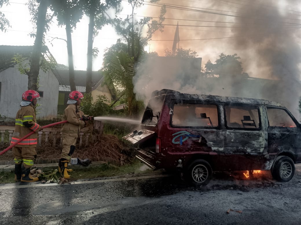 TERBAKAR: Petugas memadamkan mobil yang teebakar di Jalan Raya Temayang.