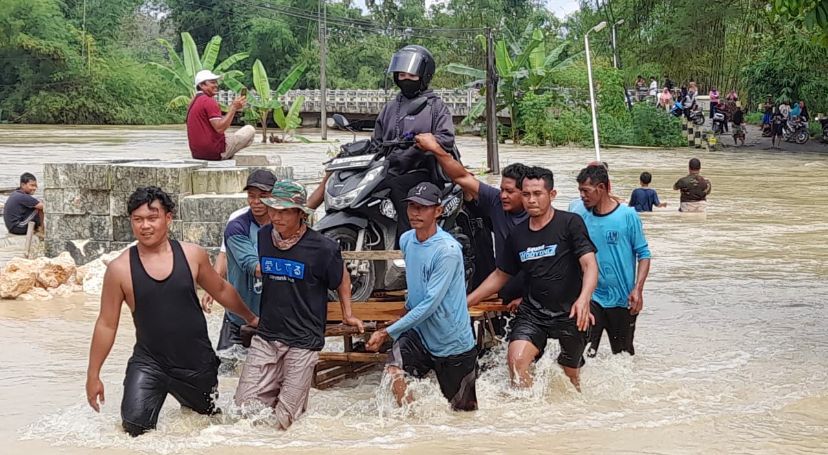 EVAKUASI: Banjir luapan Kali Lusi yang merendam sepuluh kecamatan di Blora. Masyarakat mengevakuasi pengendara motor agar bisa melintas.