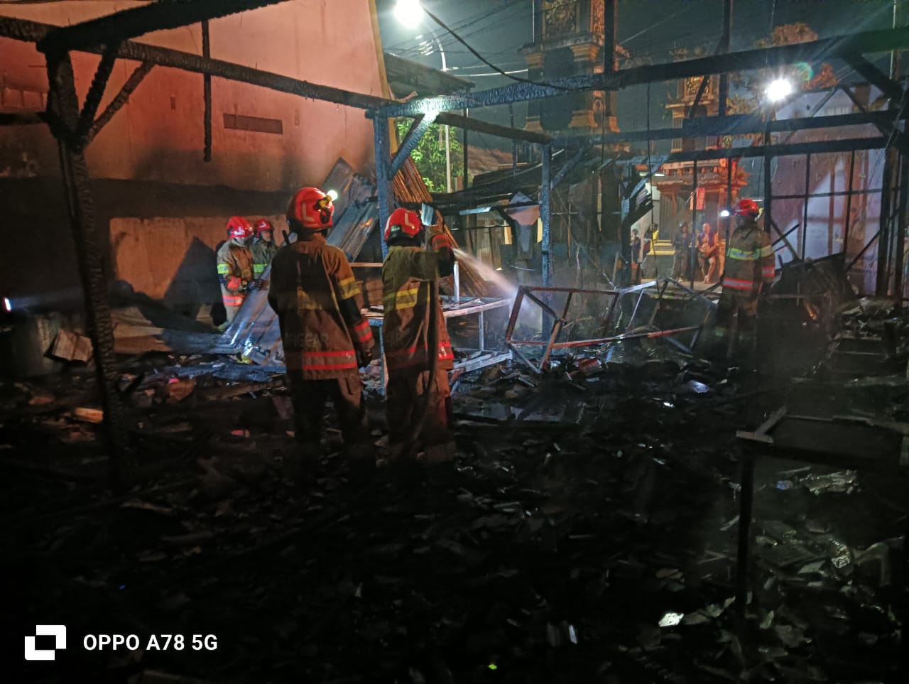 Petugas Damkarmat saat memadamkan api yang melalap rumah makan di Balen, Bojonegoro pada Minggu dini hari (22/6).