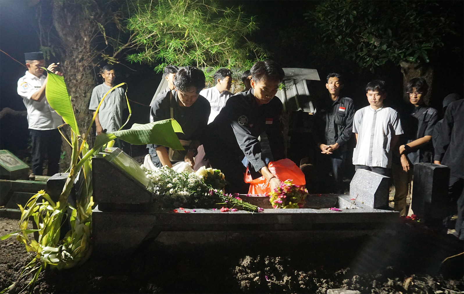 Kawan-kawan Bagus Adi Prayogo dari Universitas Gadjah Mada (UGM) menaburkan bunga di makam Bagus usai dimakamkan Kamis dinihari (3/7). (YUAN EDO/RADAR BOJONEGORO)