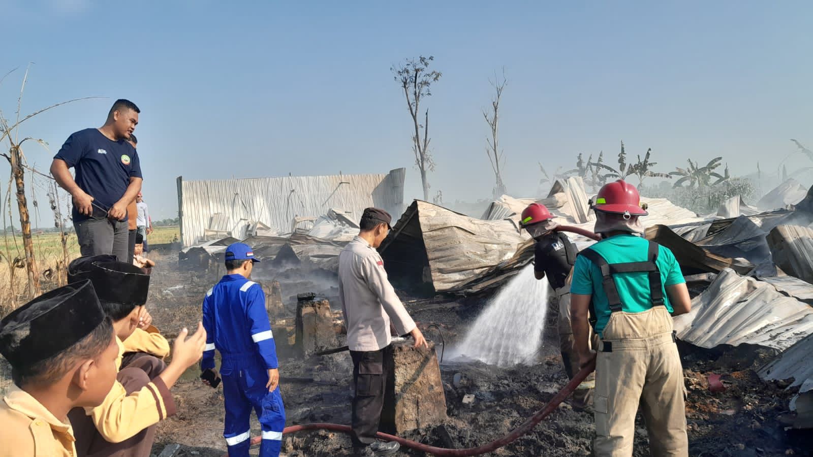 KEBAKARAN: Kandang ayam berukuran 50x12 meter yang berisi 15.000 ekor ayam hangus terbakar. Petugas pemadam kebakaran usai pedamaman, lakukan pembasahan.