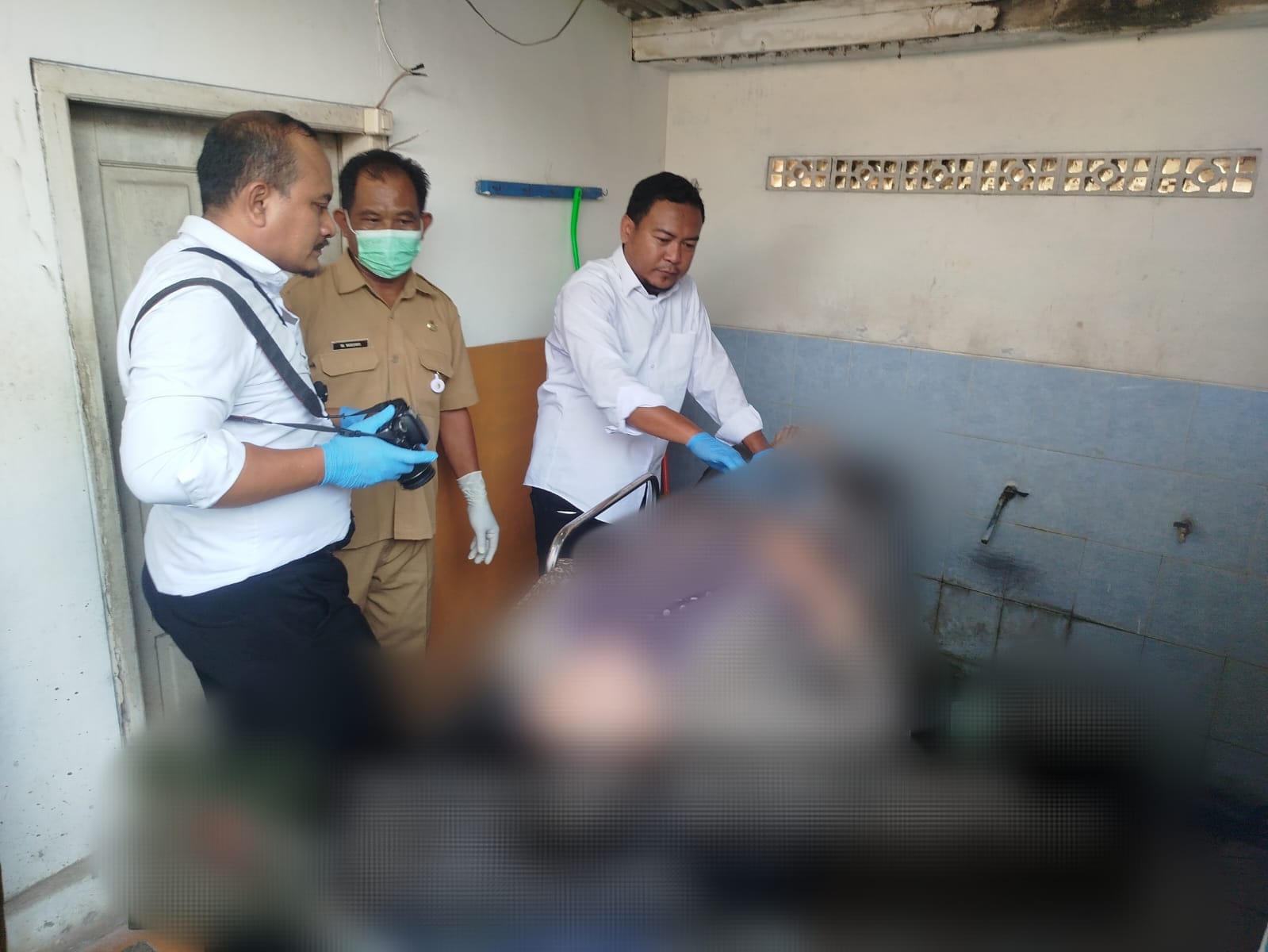 MENDADAK: Petugas mengevakuasi korban meninggal di dalam toilet Pasar Kapas. (ISTIMEWA/RADAR BOJONEGORO)